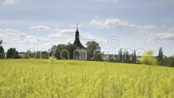 小教堂巴洛克式小教堂用油籽油菜在田野做钟楼视频的预览图