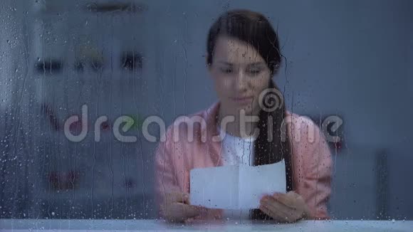 体贴的女人在雨窗后读信有怀旧的记忆视频的预览图