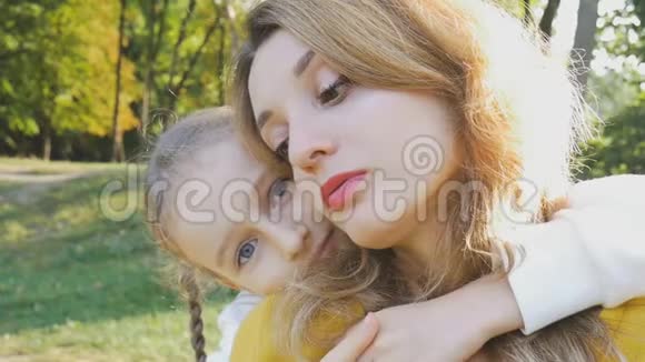 特写一幅美丽的肖像秋天的女人穿着黄色时髦的衬衫小女儿穿着蓝色的衣服花时间在视频的预览图