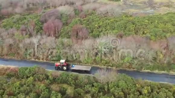 爱尔兰农村公路上拖拉机和拖车驾驶的鸟瞰图视频的预览图