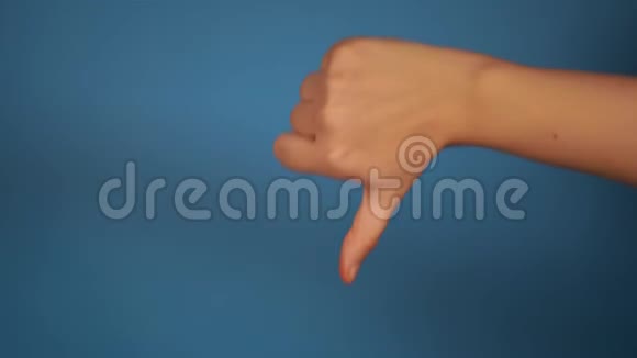 女人的手在蓝色背景下伸出拇指表示不赞成的手的特写镜头概念视频的预览图