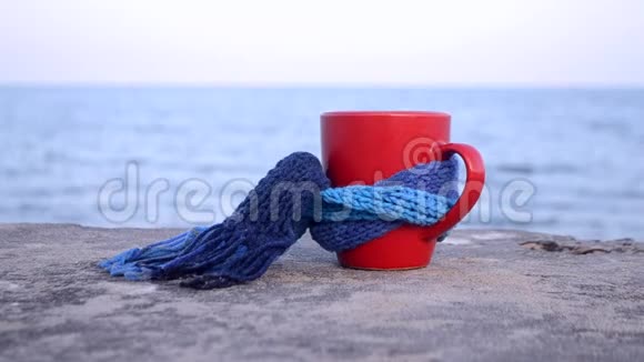 红杯配热咖啡茶用蓝色针织围巾系在石头上视频的预览图