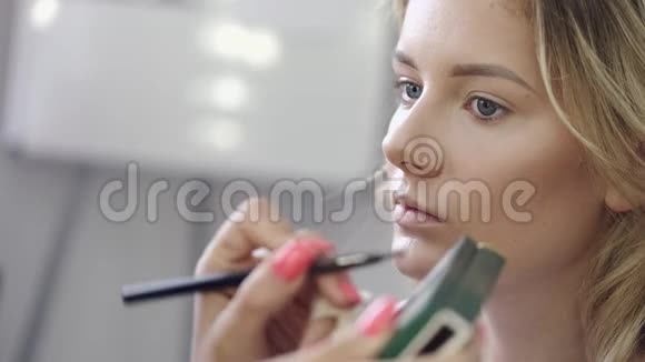 化妆师将化妆品应用于客户沙龙的面部视频的预览图