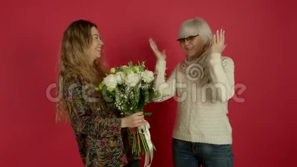 微笑的女人献花亲吻年长的母亲视频的预览图
