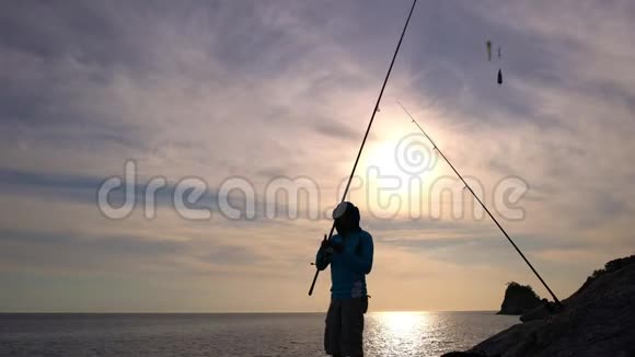 泰国普吉岛海岸岩石上的渔夫剪影美丽的日落或日出时间视频的预览图
