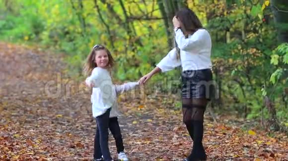 妈妈带着儿子和女儿在一个城市公园的秋天森林里散步视频的预览图