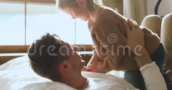 有趣可爱的孩子女儿挠痒爸爸在床上玩耍视频的预览图