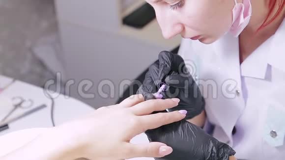美容院的女美甲师在顾客的指甲上涂上紫色的凝胶抛光剂视频的预览图