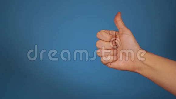 女人手在蓝色背景上伸出拇指特写手势表示赞同样的概念视频的预览图