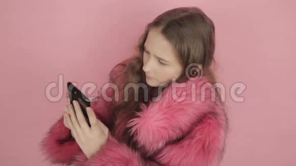 年轻漂亮的女孩在网上读笑话在黑色手机上回答信息视频的预览图