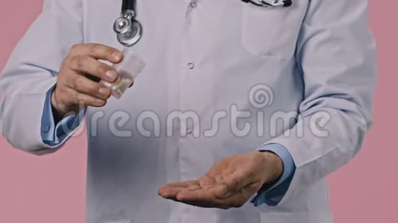 近距离观看医生在粉红色背景下将药丸倒入手掌视频的预览图