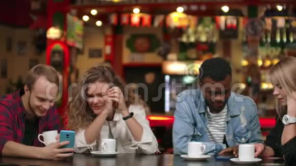 在朋友公司讲有趣的故事跨国公司的男人和女人坐在一张端着咖啡的桌子旁视频的预览图