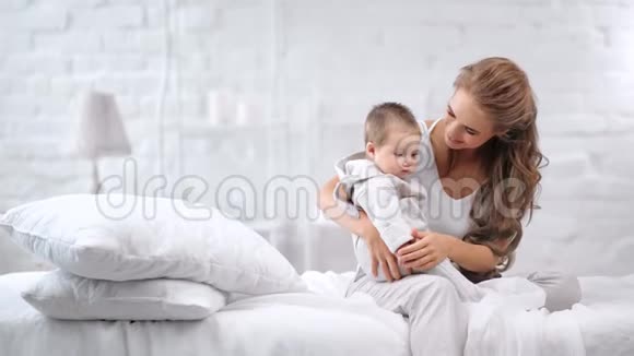 幸福的家庭年轻的女人和可爱的孩子一起放松早晨卧室的室内背景视频的预览图