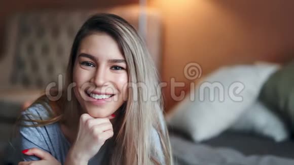 在卧室里对着镜头摆姿势的美丽金发年轻女性的特写镜头视频的预览图