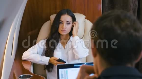 成功的女商人和商人乘坐私人飞机使用智能手机的女人男人在笔记本电脑上工作一对夫妇视频的预览图