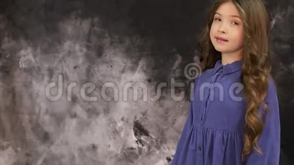 站在灰色墙边看镜头的漂亮小女孩模特儿视频的预览图