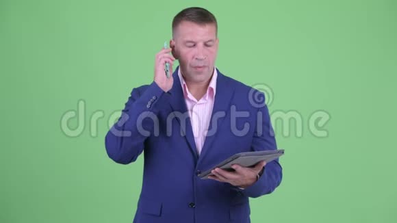 成熟有男子气概的商人使用手机和数码平板电脑视频的预览图