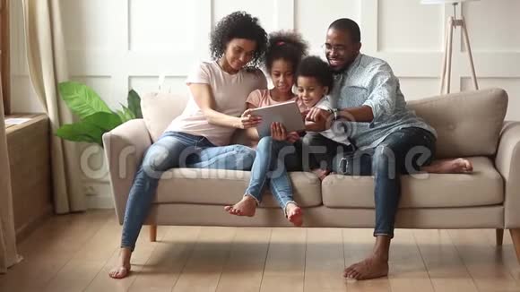 有孩子的非洲家庭在室内玩平板电脑视频的预览图