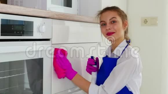 打扫房间用粉红色手套和粉红色抹布擦拭白色表面一个涂口红的女孩做清洁视频的预览图