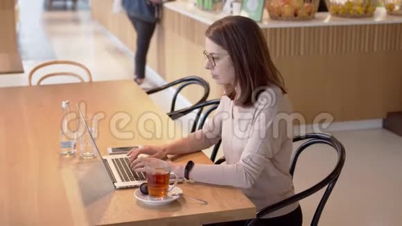 在咖啡馆里一个专心致志的女人在桌上喝茶视频的预览图