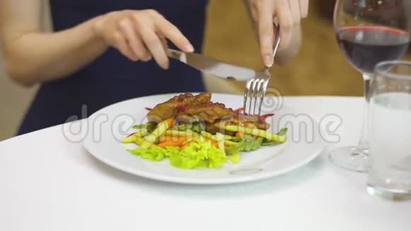 穿着晚礼服的女士用叉子和刀子吃蔬菜猪肉视频的预览图