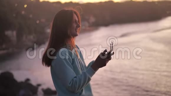 年轻女子在山上控制着一架无人驾驶飞机概念日落4k视频的预览图