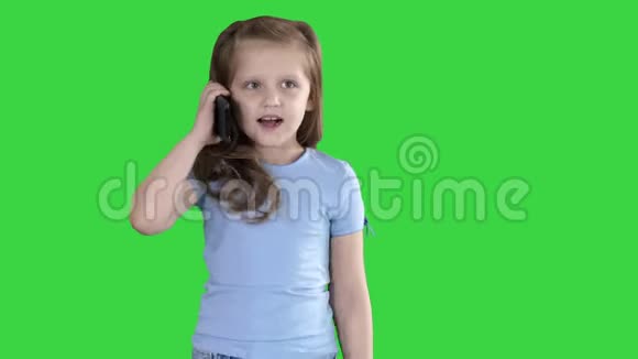 小女生在绿色屏幕上行走时用智能手机打电话Chroma键视频的预览图