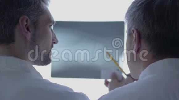 后视两位男医生检查x光讨论穿白色长袍的人在实验室里谈论人体骨骼视频的预览图