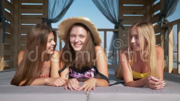 快乐的女性朋友微笑的漂亮女孩穿着泳装在暑假躺在海滨长廊的平房里视频的预览图