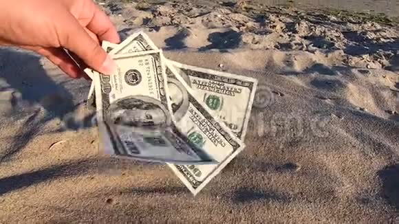 女孩拿着300美元的钞票在沙滩上视频的预览图
