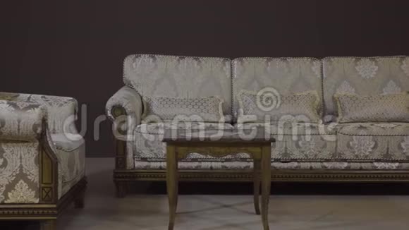 沙发配有纺织室内装潢椅子和带有木腿雕刻的咖啡桌视频的预览图