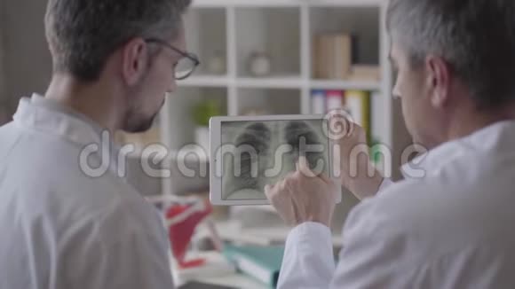 两位有经验的男医生在药片上检查肺部x线讨论医学保健和视频的预览图