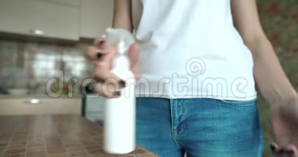 厨房里的一个女孩用防腐剂喷洒她的手以消毒冠状病毒COVID19流行病视频的预览图