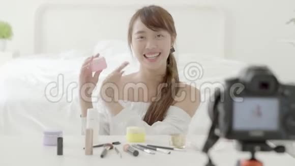 美丽的亚洲年轻女性在家里用videto和vlog化妆视频的预览图