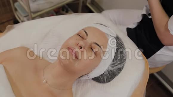 女人躺在沙发上在美容院戴着透明的织物抗衰老面具视频的预览图
