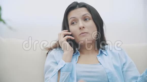 开朗的黑发女人正在打电话一边嚼零食慢动作4K视频的预览图