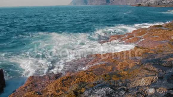 黄色的岩石沸腾的绿松石冲浪耀眼的正午阳光照亮了熔岩岩岸积极的概念视频的预览图