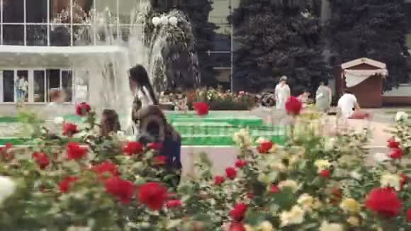 女孩在城市喷泉和玫瑰花圃附近嬉戏奔跑视频的预览图