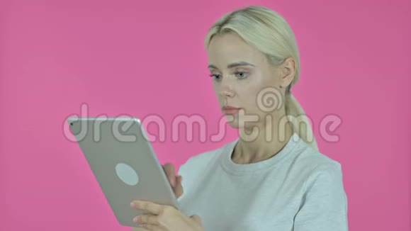 年轻女性在平板电脑上浏览互联网粉红背景视频的预览图