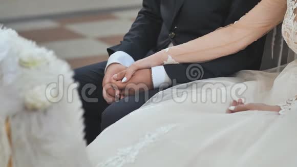新婚夫妇的手在教堂举行的天主教婚礼上合在一起视频的预览图