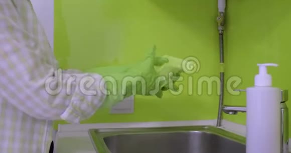 厨房里的女人带着手套海绵和抹布海绵上有洗涤剂泡沫视频的预览图
