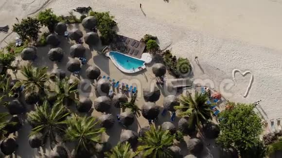 在美丽的白沙海海岸豪华海景度假胜地海滩伞的茅草屋顶的鸟瞰视频的预览图