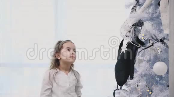 小女孩正在家里装饰一棵圣诞树上面有蝴蝶结蝴蝶结和袜子视频的预览图