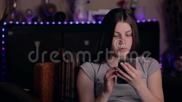 震惊女孩通过智能手机阅读信息在家拿着手机让年轻女人心烦意乱坏消息概念视频的预览图