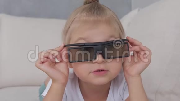 一个戴3D眼镜的小女孩专注地看着电视屏幕视频的预览图