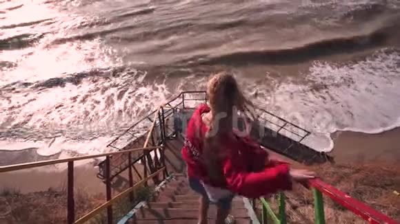 女孩沿着海滩上的老台阶走向大海视频的预览图