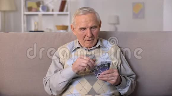 愤怒的老人坐在沙发上拿着欧元钞票社会不安全视频的预览图