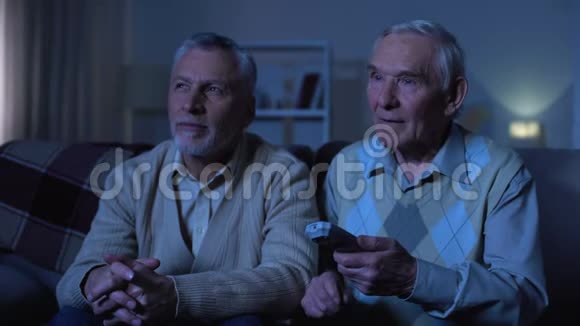 老年男性朋友转换频道晚上在养老院休闲视频的预览图