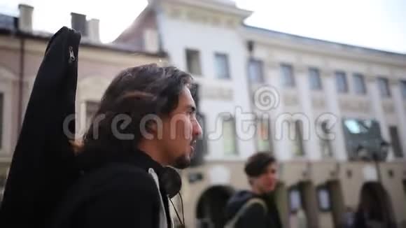 一个留着长发的男人在拥挤的街道上散步的年轻朋友视频的预览图