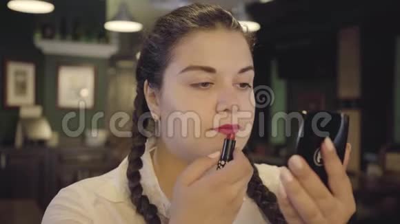 有魅力自信丰满的女人的肖像在餐厅里用鲜红的口红画嘴唇两个人的女孩视频的预览图
